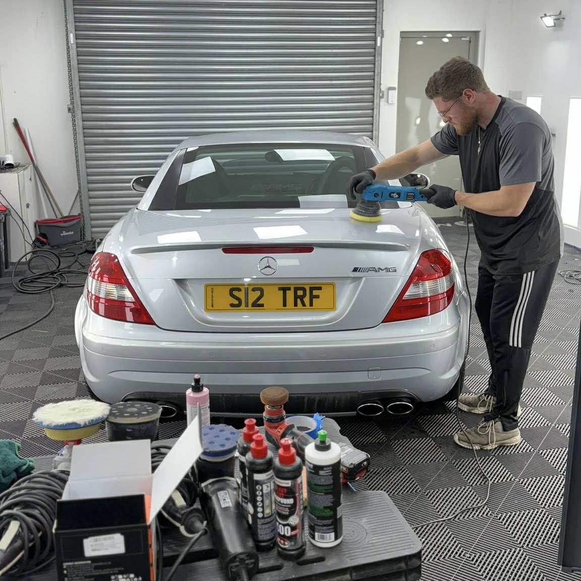 Machine polishing a silver Mercedes SLK AMG in the detailing bay